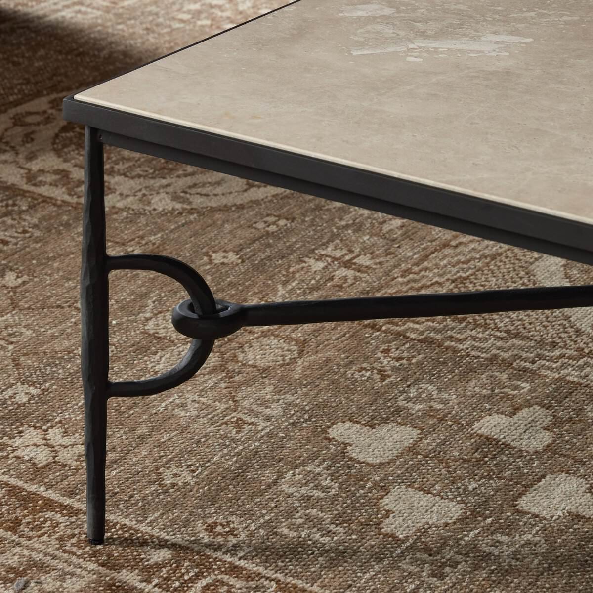 Close up of Four Hands Babylon Coffee Table in Lunar Marble against a rust rug at Addison West