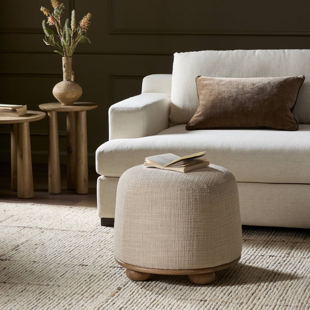 Four Hands Bilbury Ottoman in Saxon Sand in a living room with green walls at Addison West
