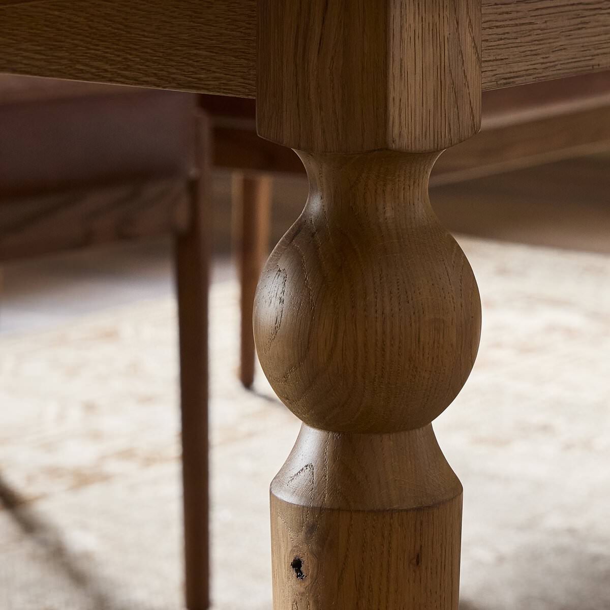 Close up of Four Hands Blinn Oval Leaf Extension Dining Table 88"-127" in Worn Oak Veneer on a white background at Addison West