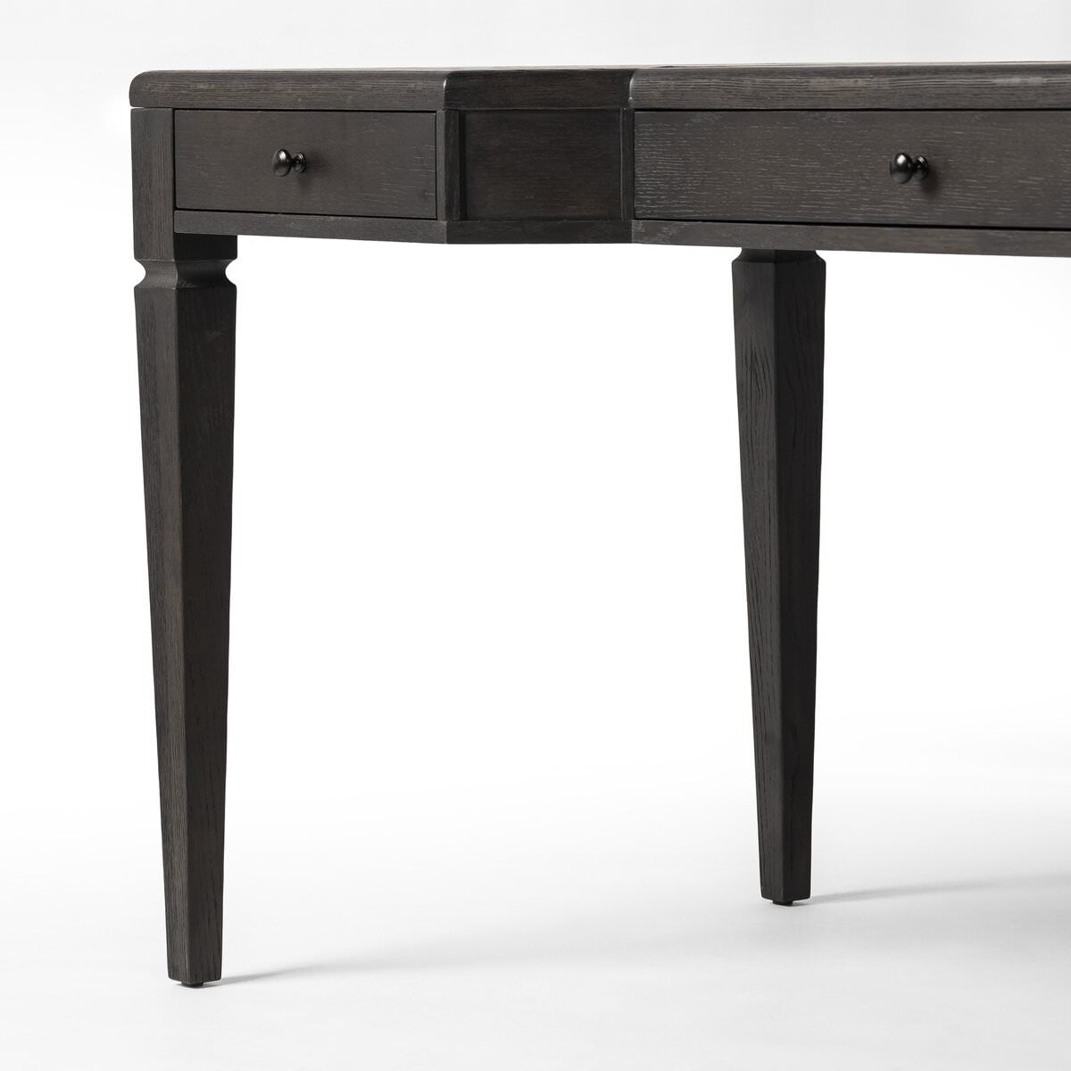 Close up of Four Hands Claude Desk in Distressed Black Oak Veneer on a white background at Addison West