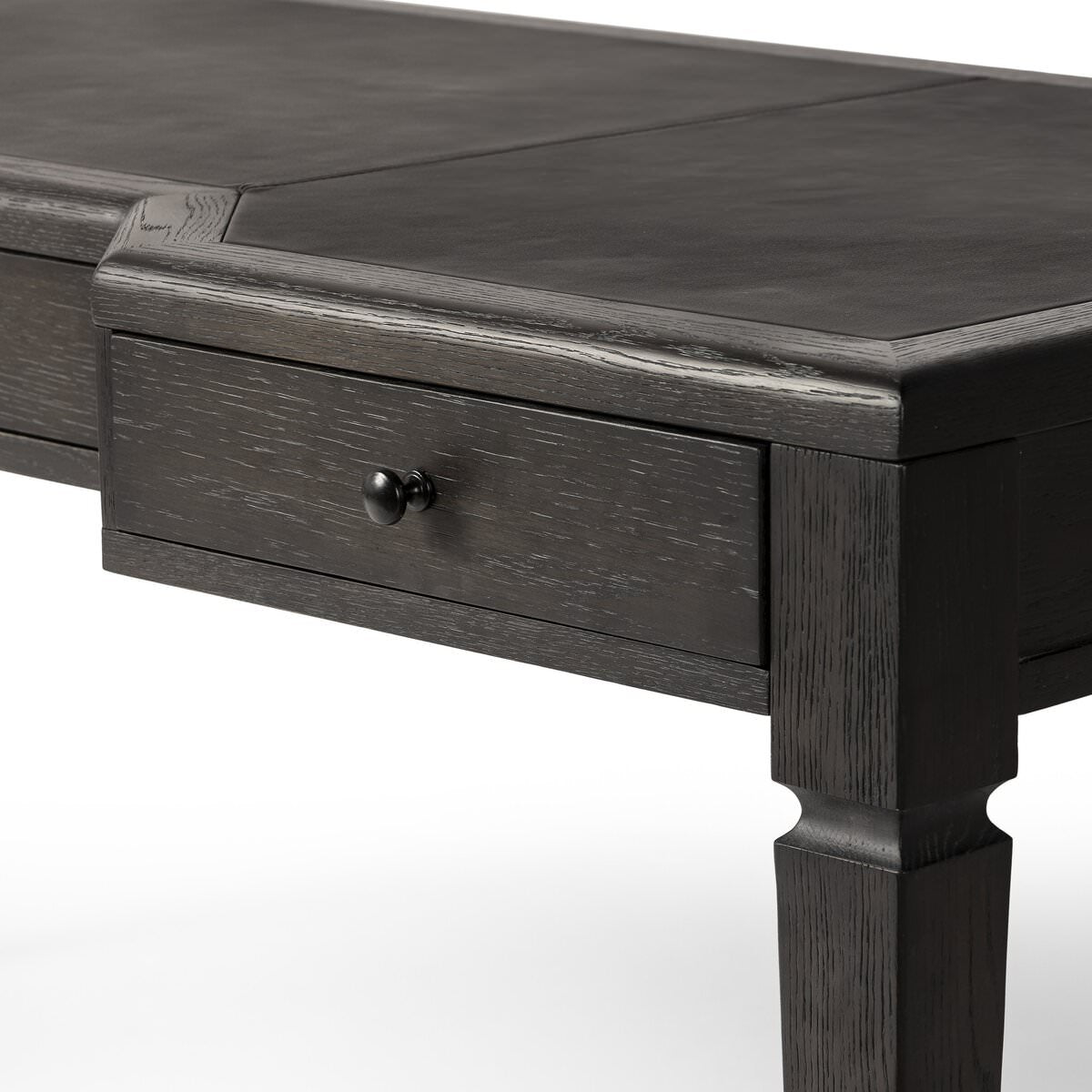 Close up of Four Hands Claude Desk in Distressed Black Oak Veneer on a white background at Addison West