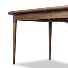 Close up of Four Hands Harper Oval Extension Dining Table 84-104" in Toasted Walnut on a white background at Addison West
