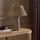 Four Hands Nessa Table Lamp in Antique Brass Iron on a table at Addison West