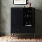 Four Hands Trey Bar Cabinet in Black Wash Poplar in a room with dark walls