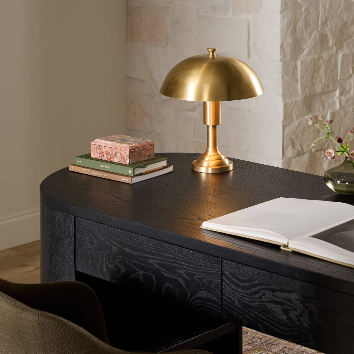 Four Hands Trieste Table Lamp in Raw Brass on a desk at Addison West
