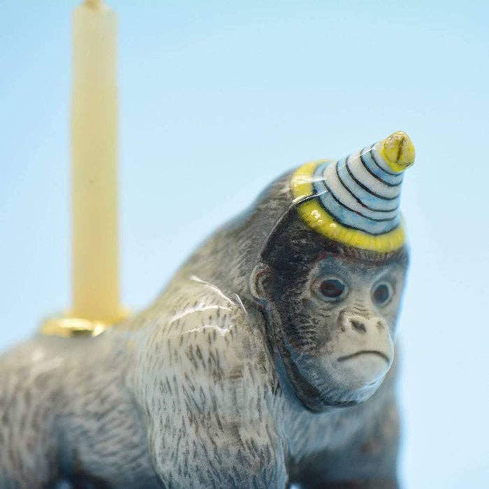 Ceramic Gorilla Cake Topper with blue and yellow birthday hat on a blue background