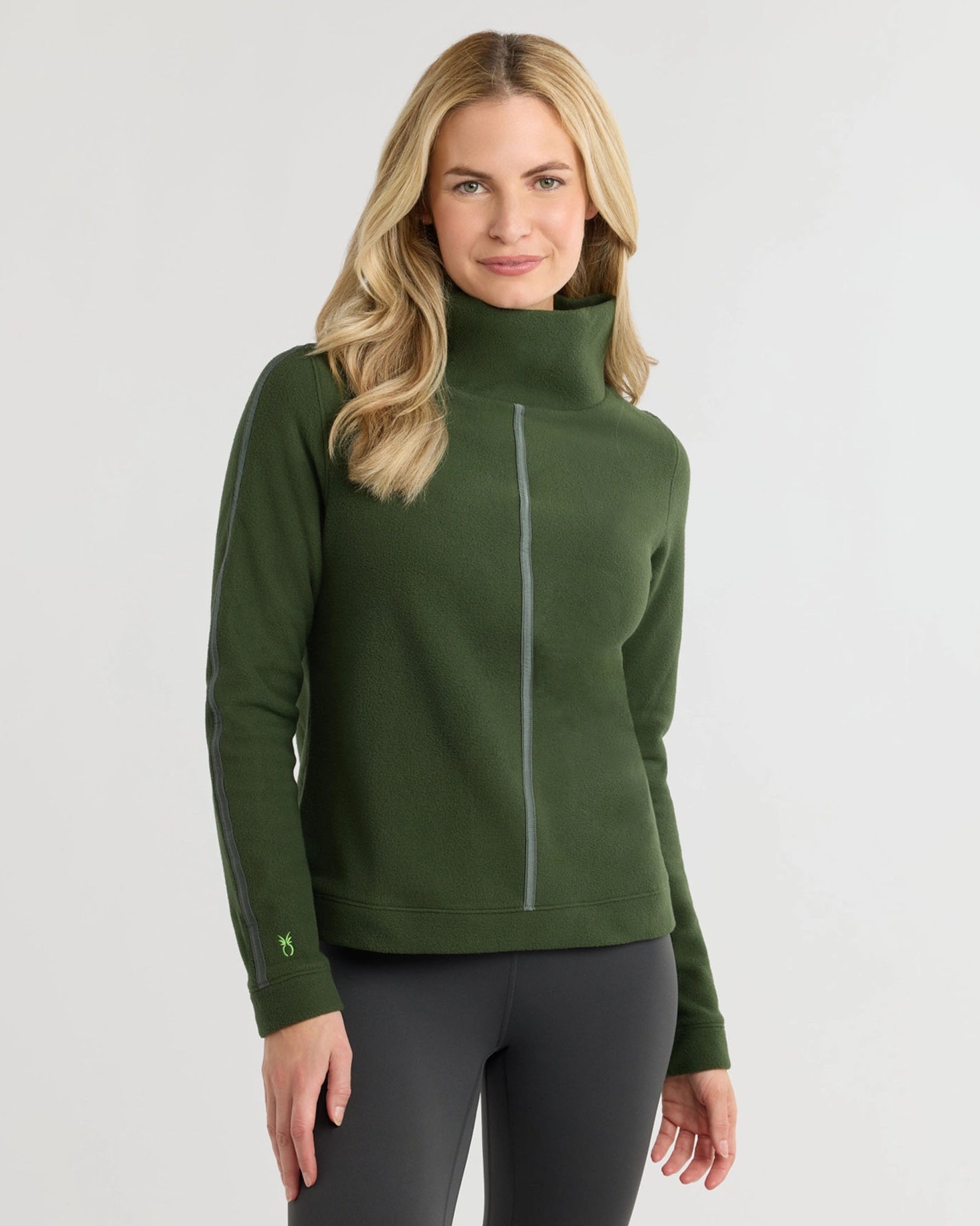 DWoman wearing Dudley Stevens Heyward Vello Fleece Turtleneck in Spruce sweater with dark colored pants on a plain background.