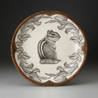 Decorative plate with a chipmunk illustration and leaf patterns on a dark background