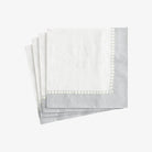 Set of folded gray napkins with white trim on a light gray background