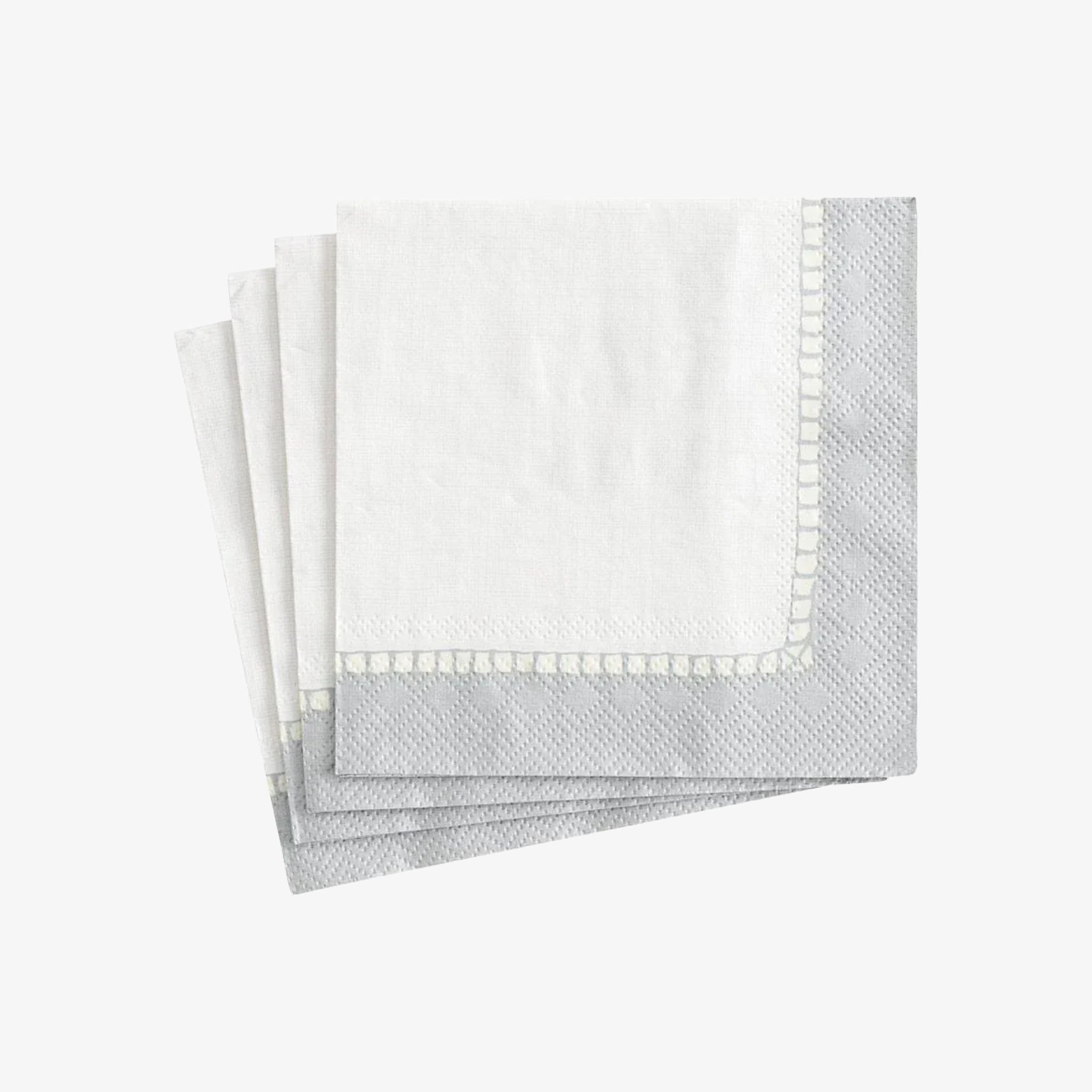 Set of folded gray napkins with white trim on a light gray background