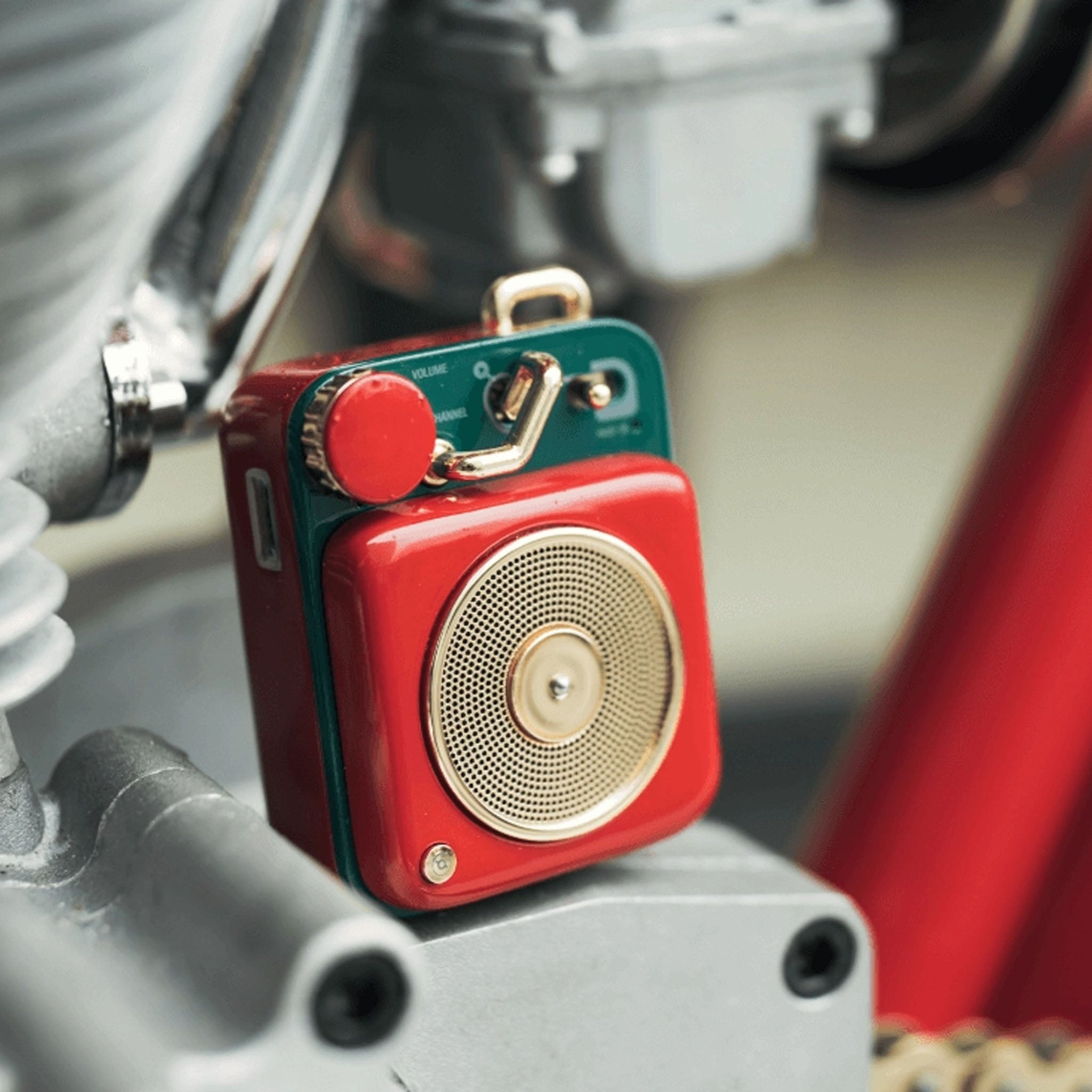 Muzen Button Mini Candy Bluetooth Speaker in Scarlet Red sitting on a metal block