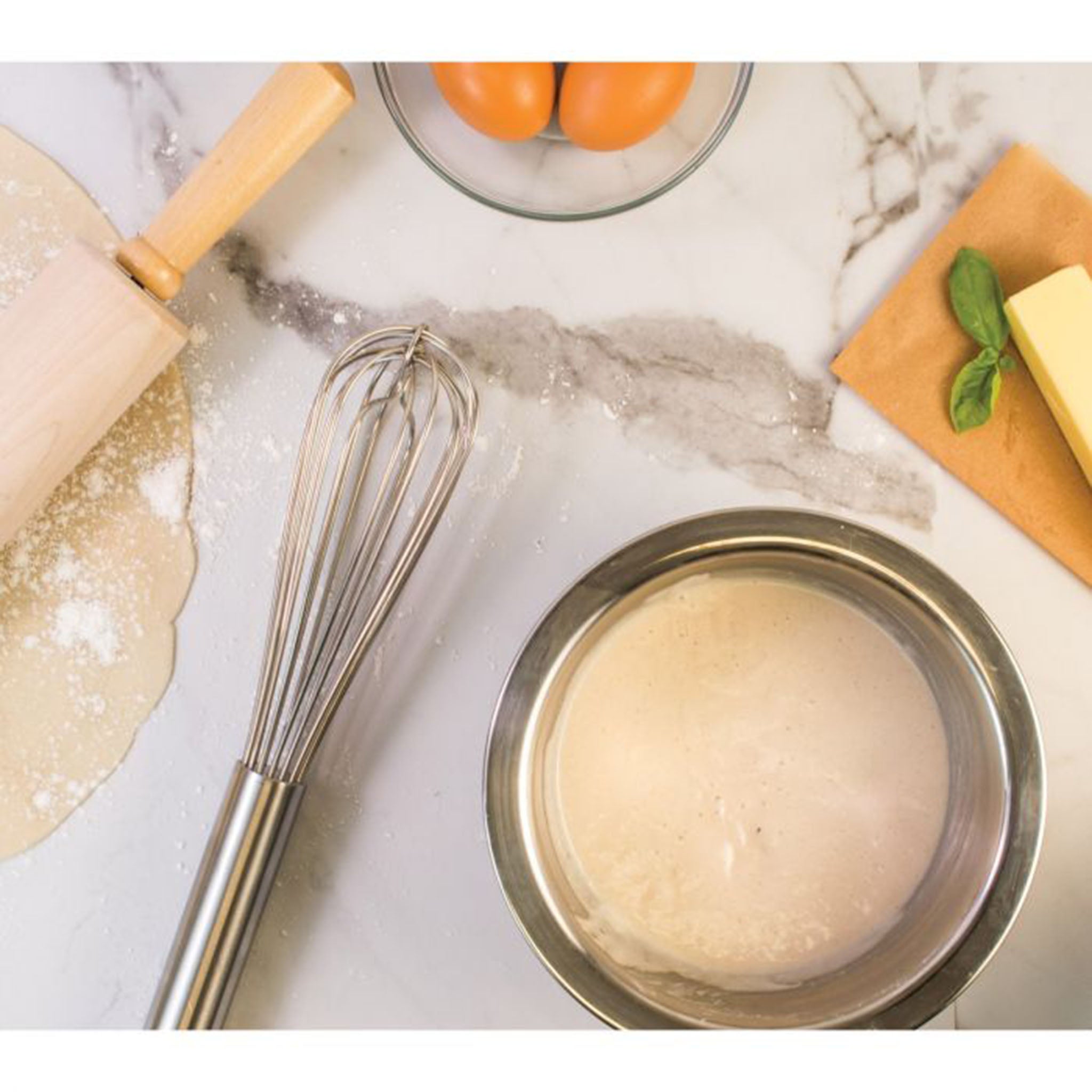 Bowls of batter and baking utensils on a marble counter including 12" Stainless steel French Whip Whisk
