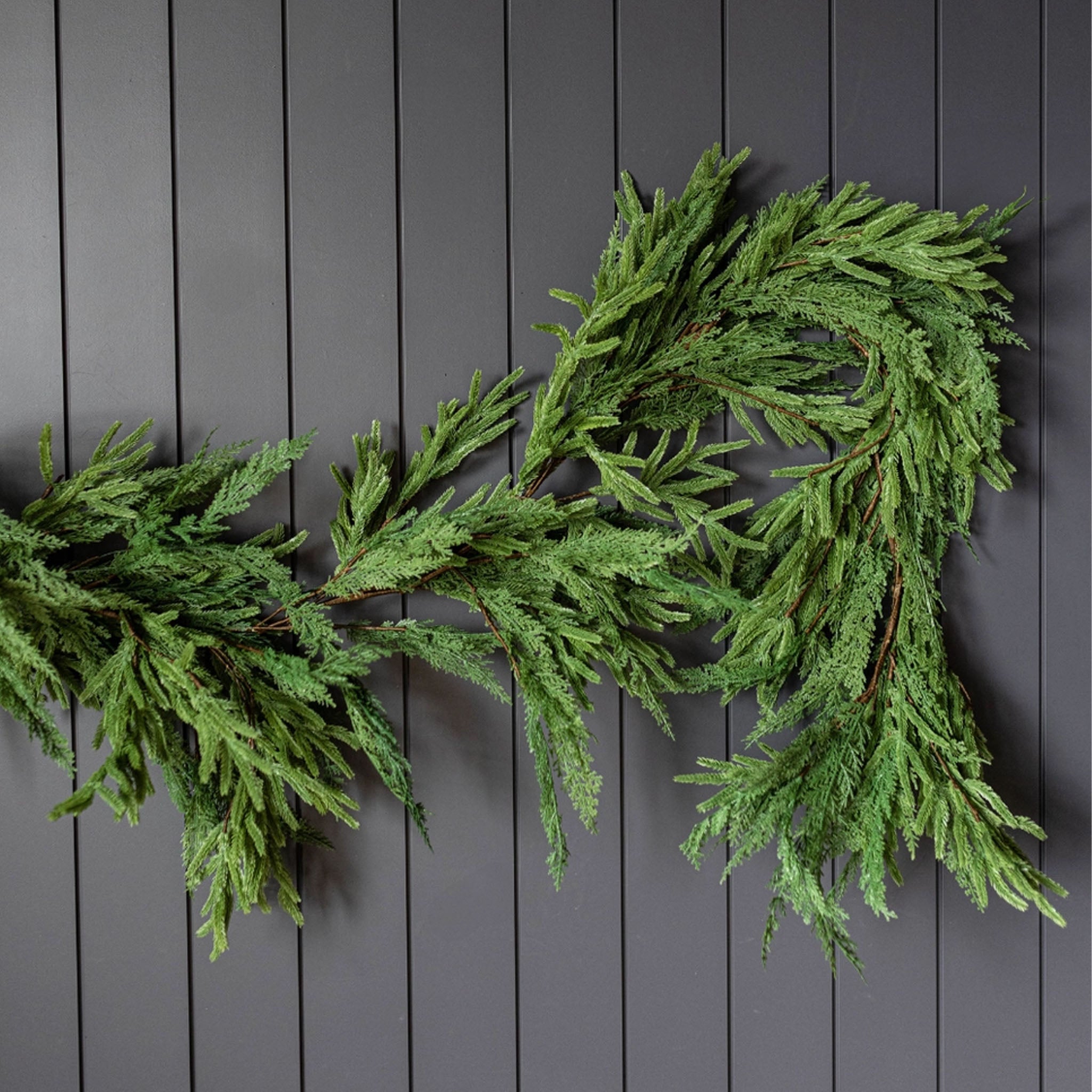 Norfolk & Cypress Mix Real Touch Faux Garland, 9ft on a black wall at Addison West
