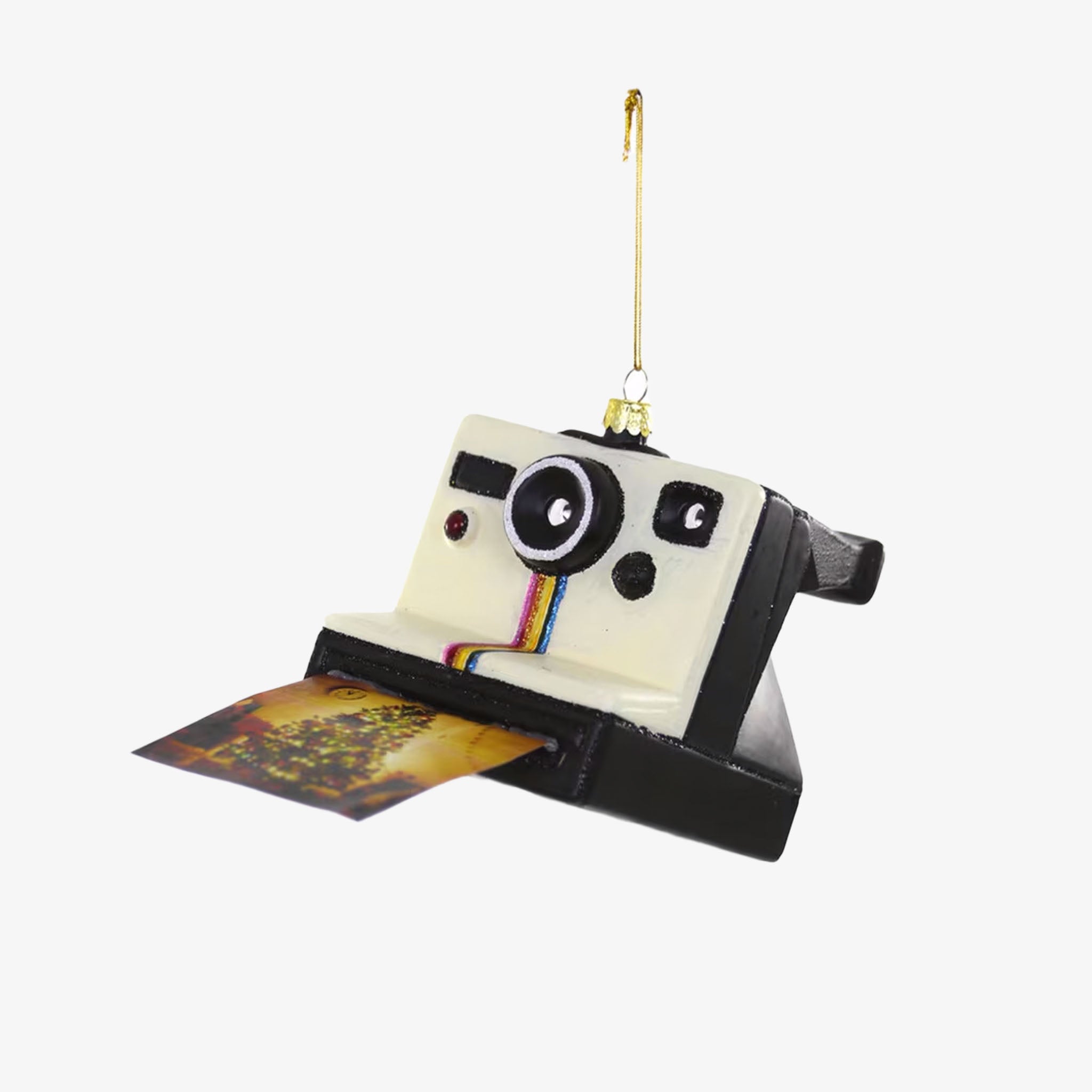 A decorative ornament shaped like a Polaroid camera with a black and white body, a colorful film slot, and a string for hanging.
