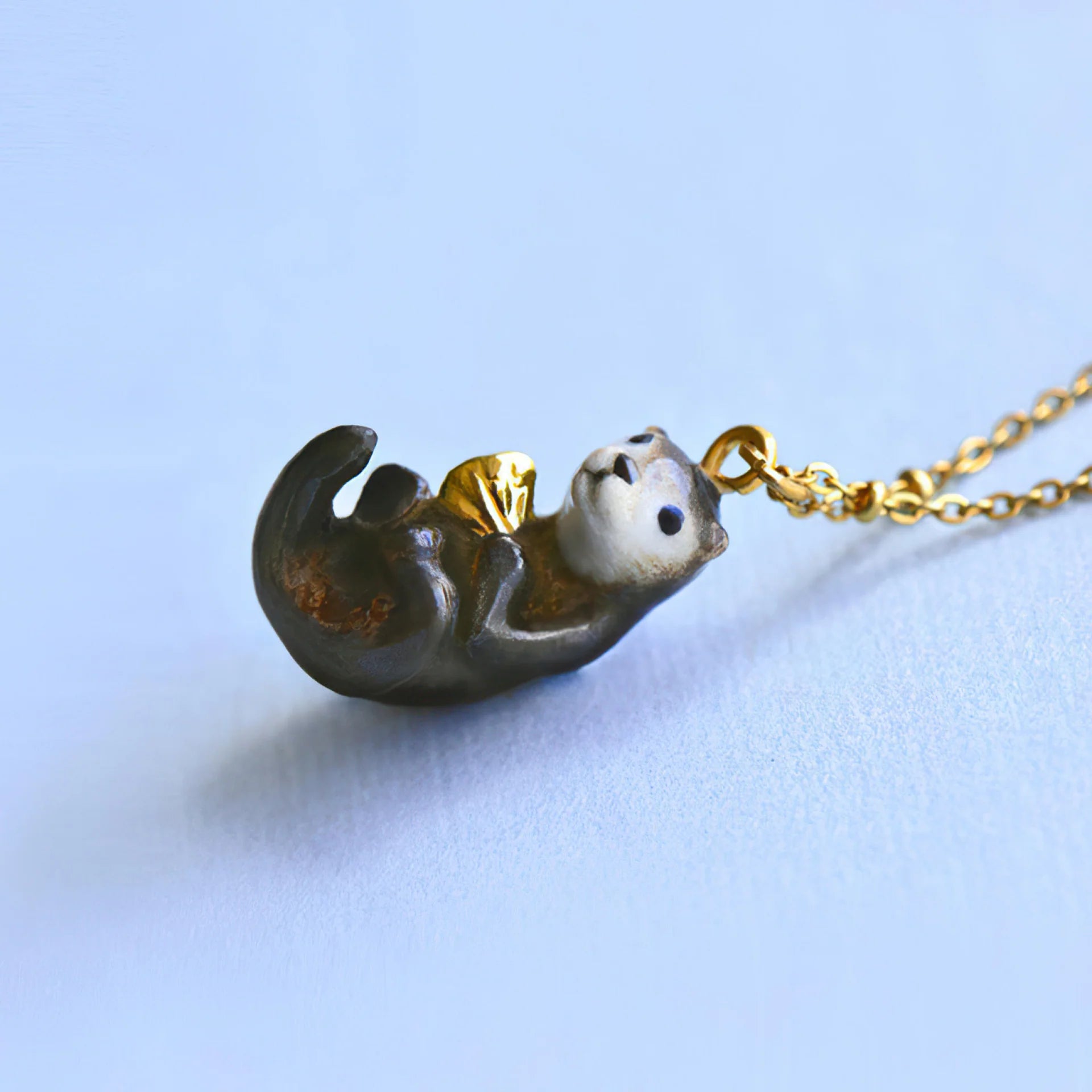 Camp Hollow porcelain otter necklace on a blue background