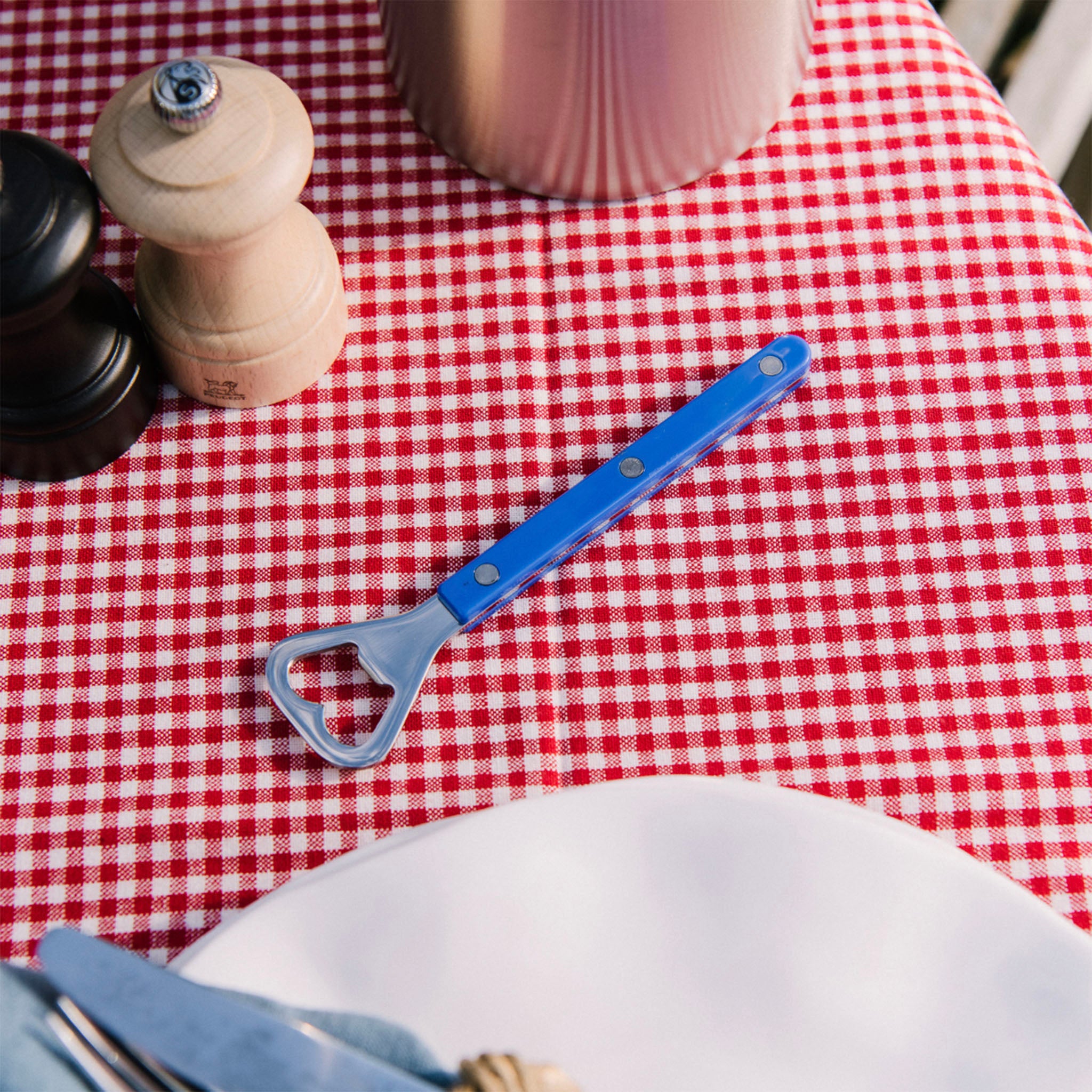 Sabre Bottle Opener in Blue on a red check table cloth