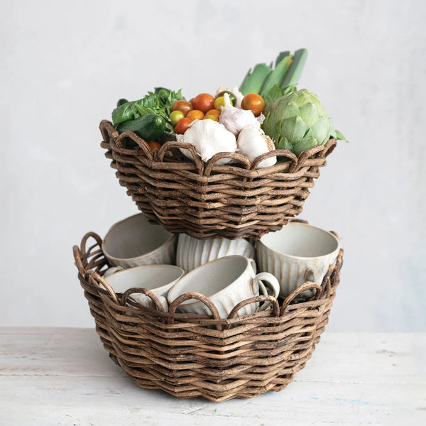 Two Scalloped Edge Woven Vine Baskets stacked on top of each other with vegetables and fruits inside on a white counter surface