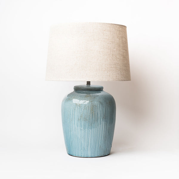 Blue green creative coop brand stoneware lamp with linen shade on a white background