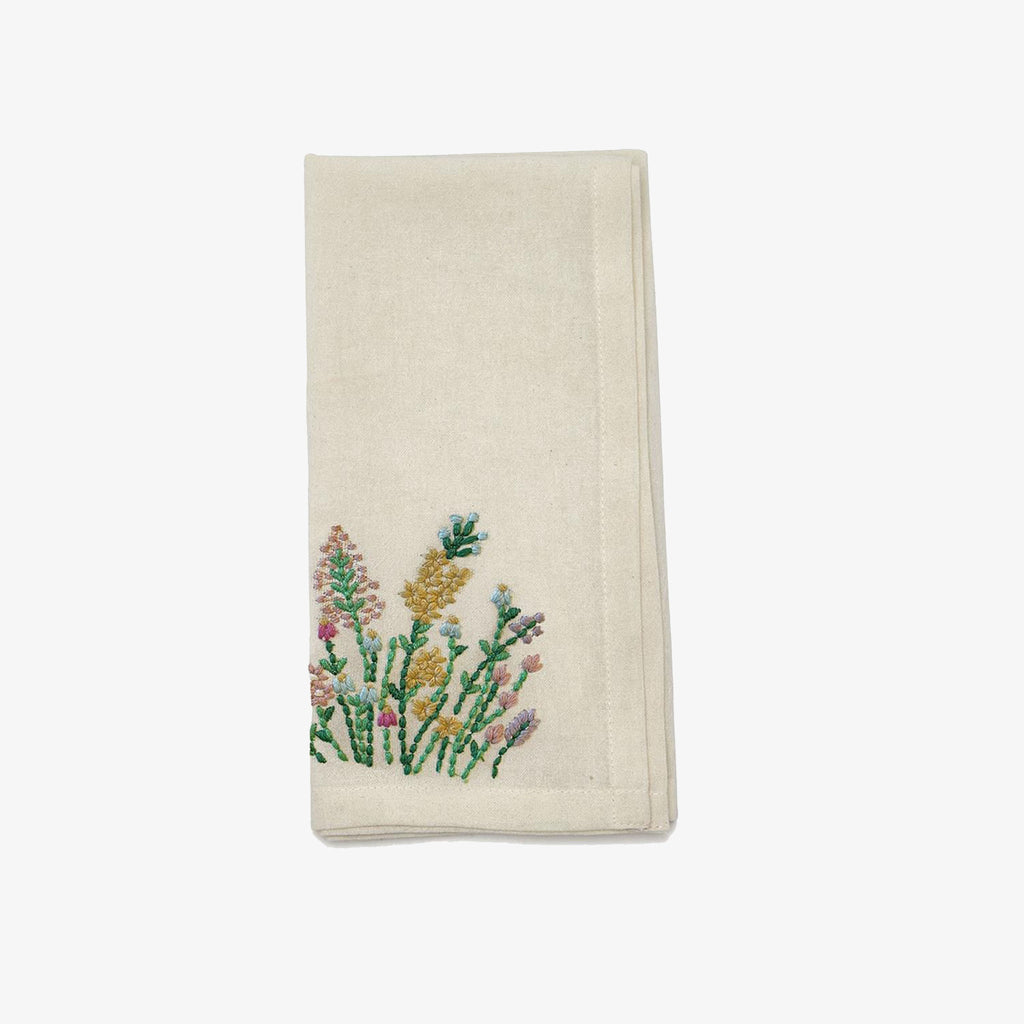 White cotton napkin with pastel wildflower embroidery on a white background