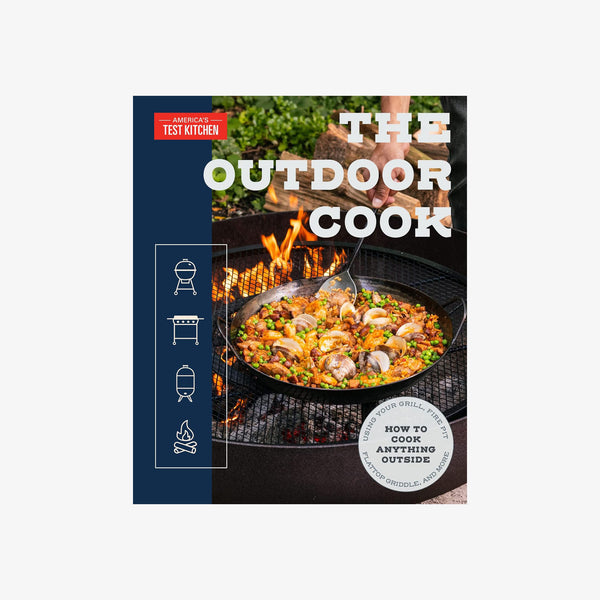 Front cover of book titled 'The Outdoor Cook: How to Cook Anything Outside Using Your Grill' with a grill and paella in a cast iron pan on a white background