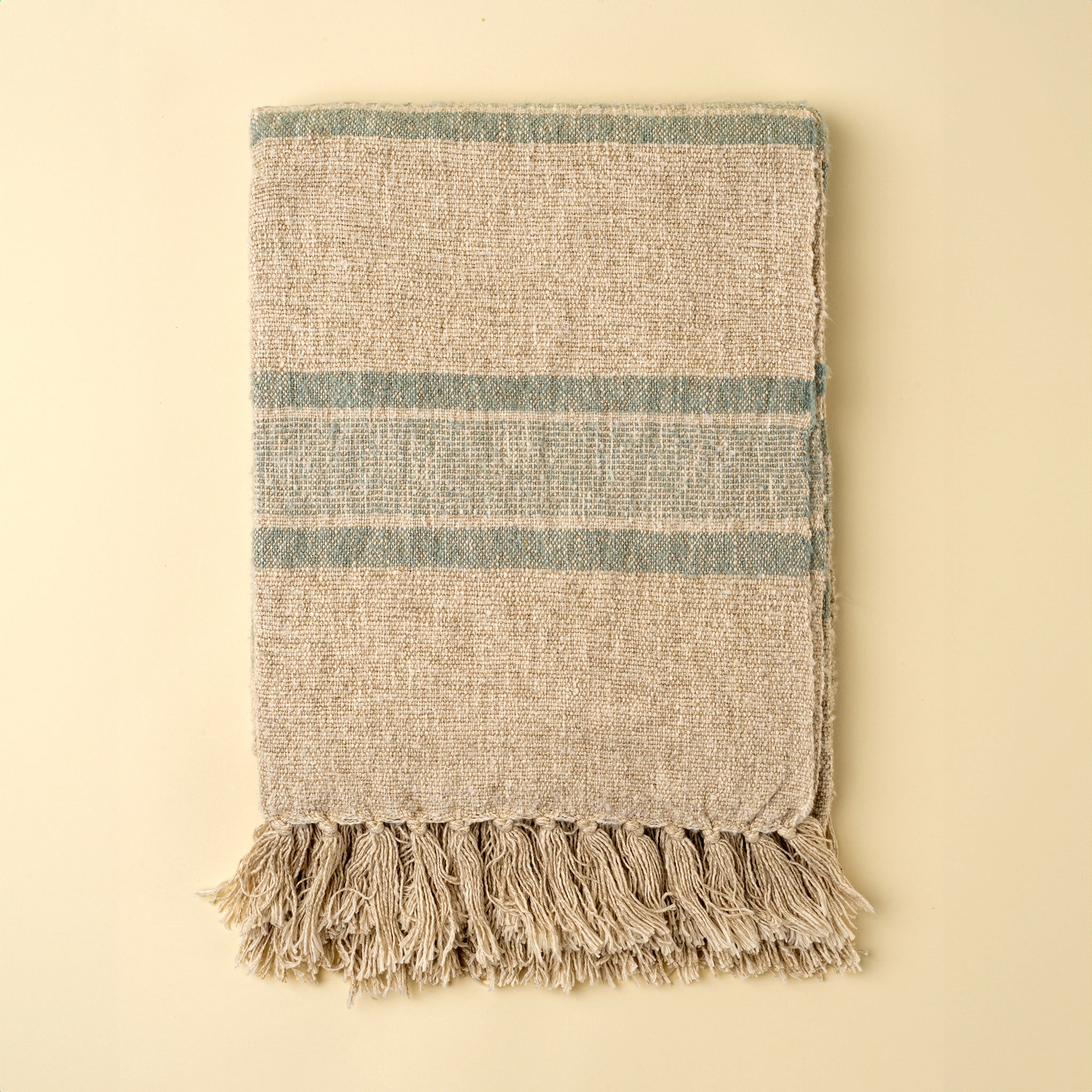 Tulum Striped Throw in Blue on a beige background at Addison West