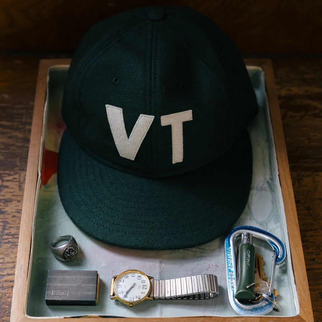 Warren Farm League Ballcap in Green Mountain State on a wood background at Addison West