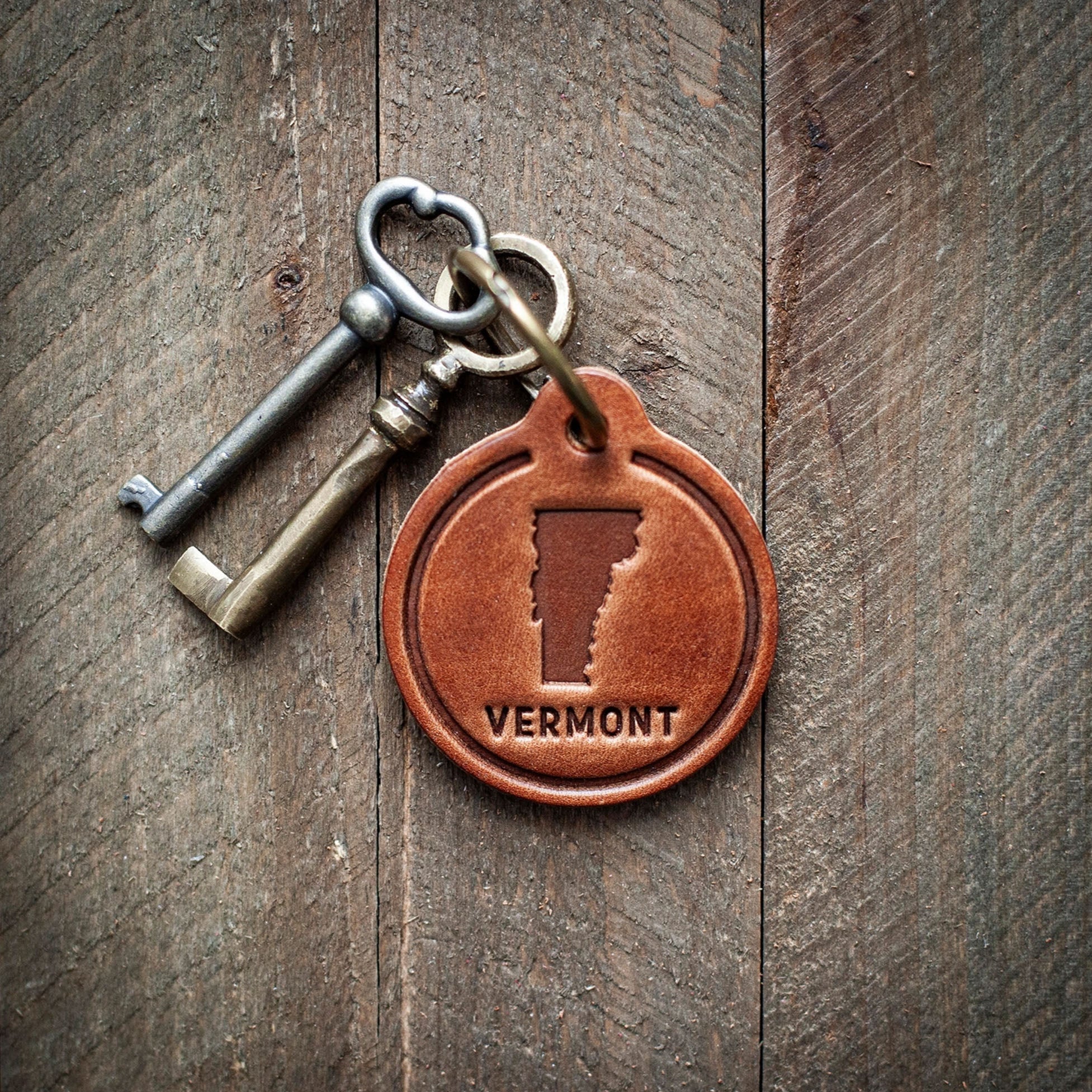 Vermont State Leather Keychain on a wood background at Addison West