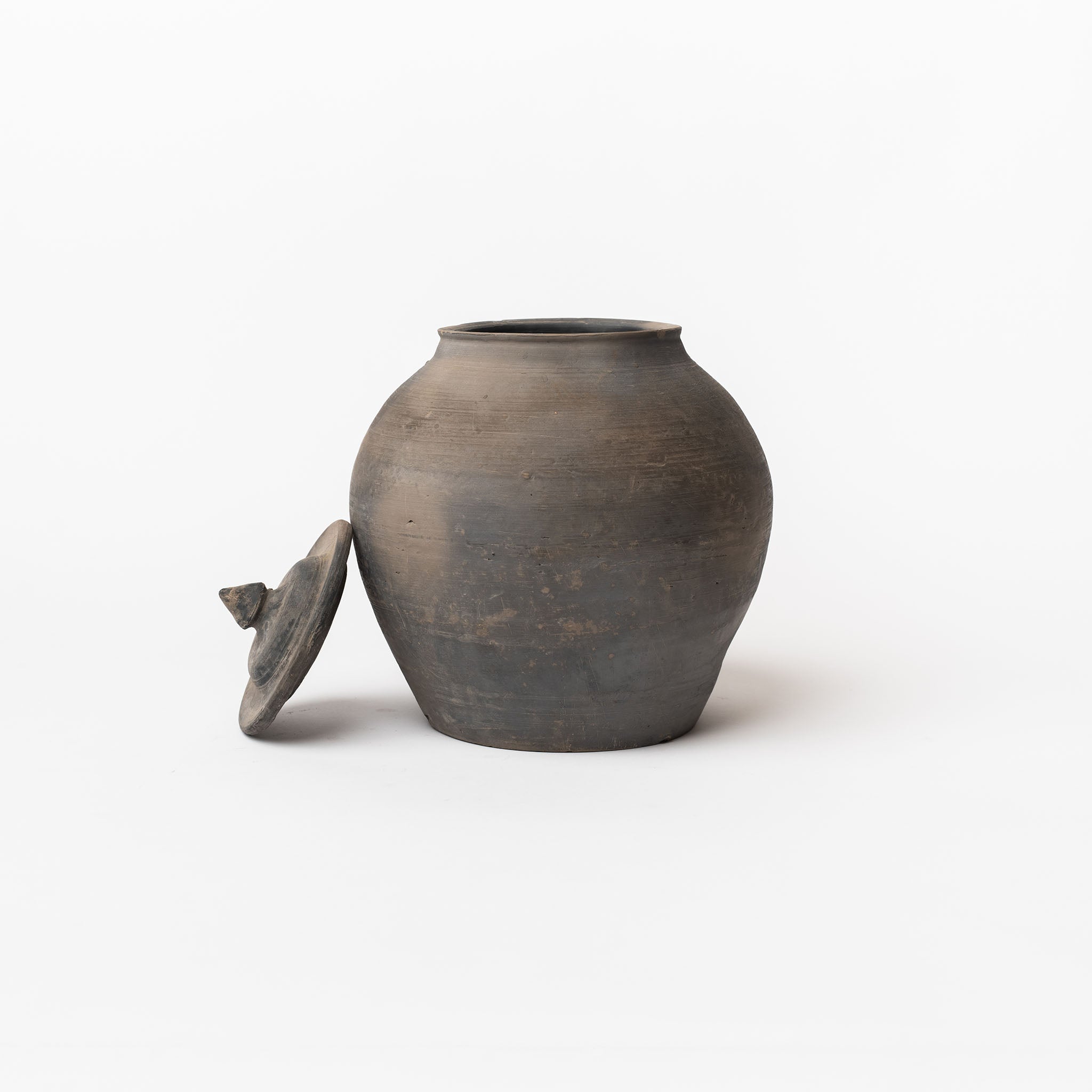 Black terracotta lidded jar on a white background