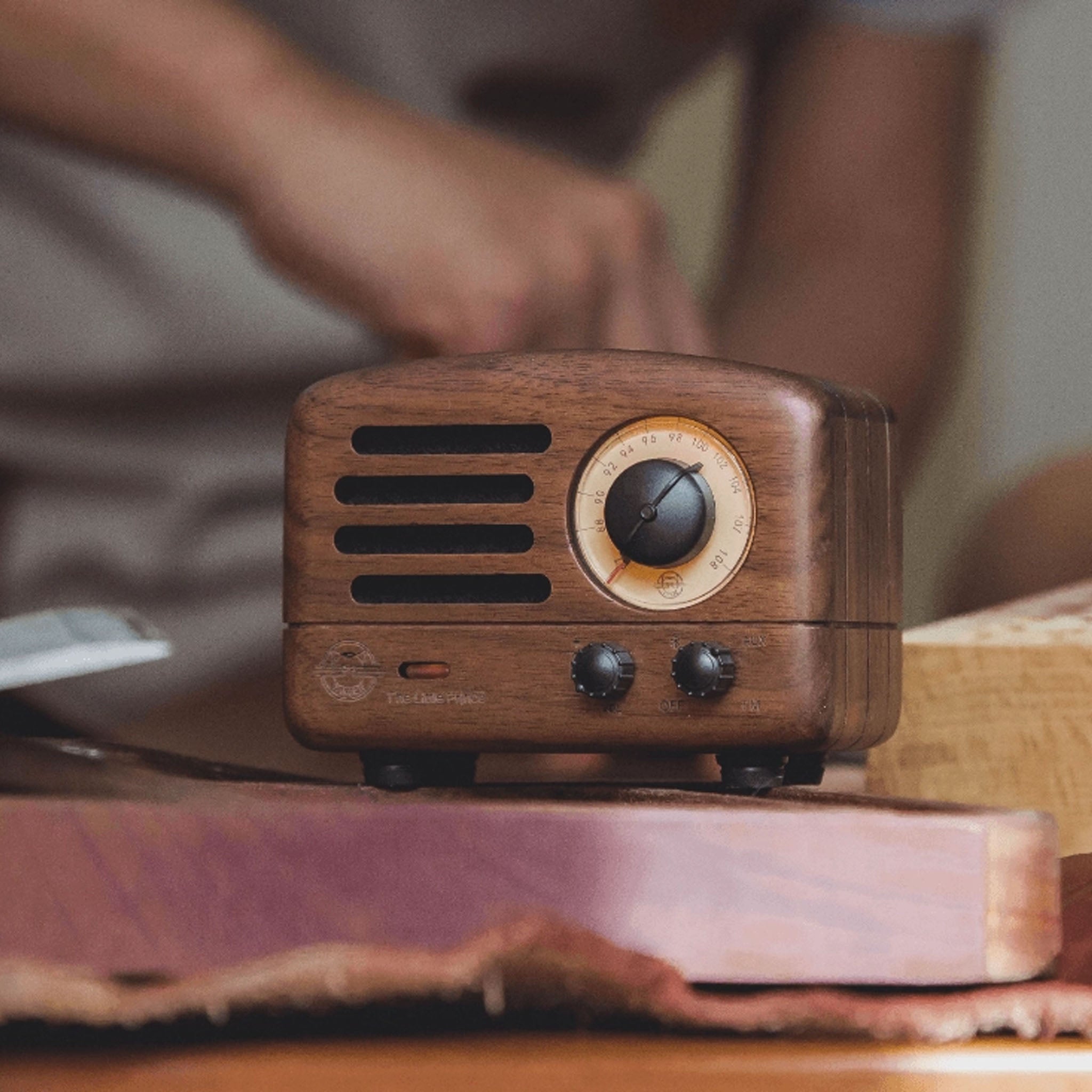 Muzen OTR Wireless FM and Bluetooth Speaker in Walnut on a wood table