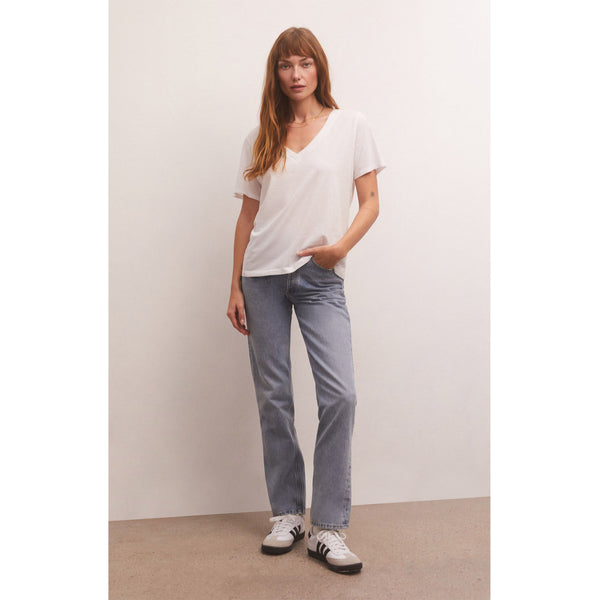 Model wearing loose fitted Z Supply Girlfriend V-Neck Tee in White with jeans and sneakers in front of a white wall
