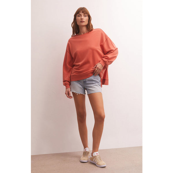 Model wearing Z Supply Modern Weekender in Lava with cut off jean shorts in front of a white wall