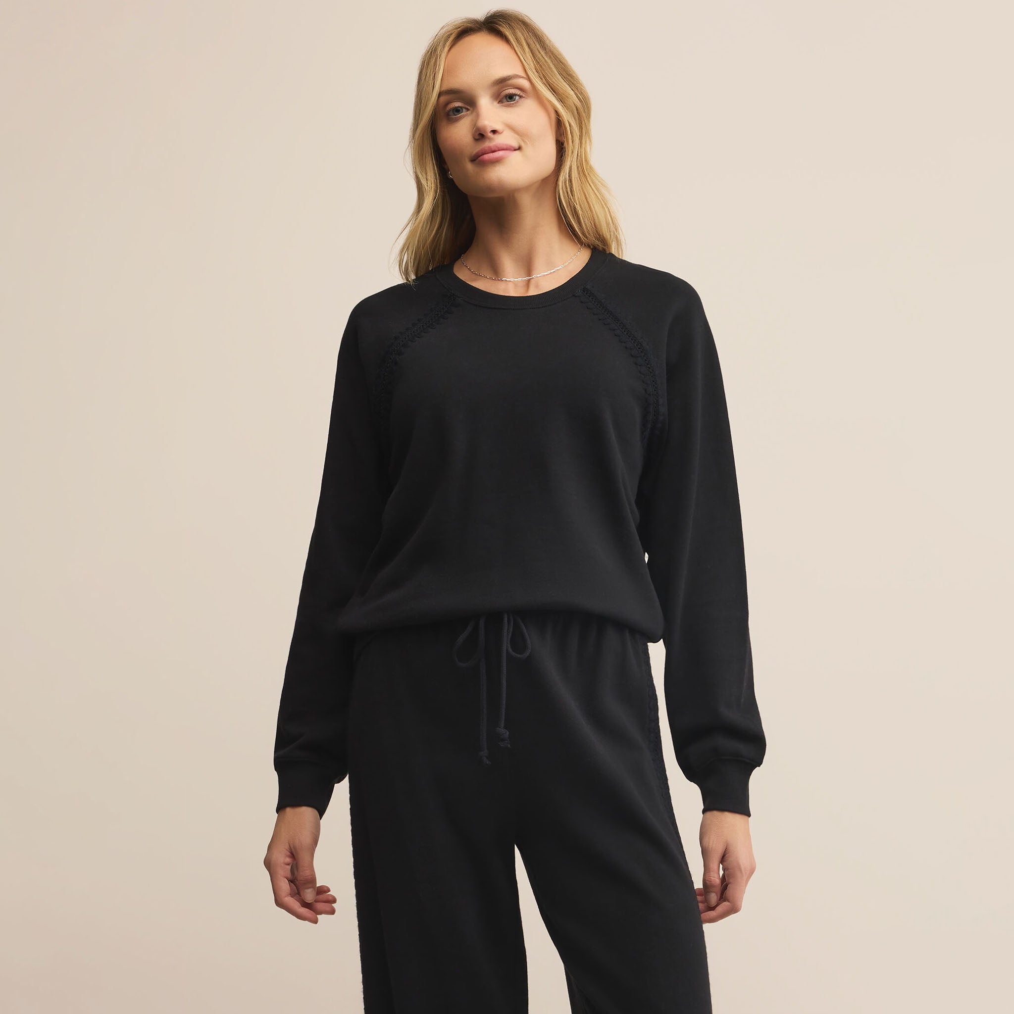 Woman wearing Z Supply All Around Sweatshirt in Black on a beige background
