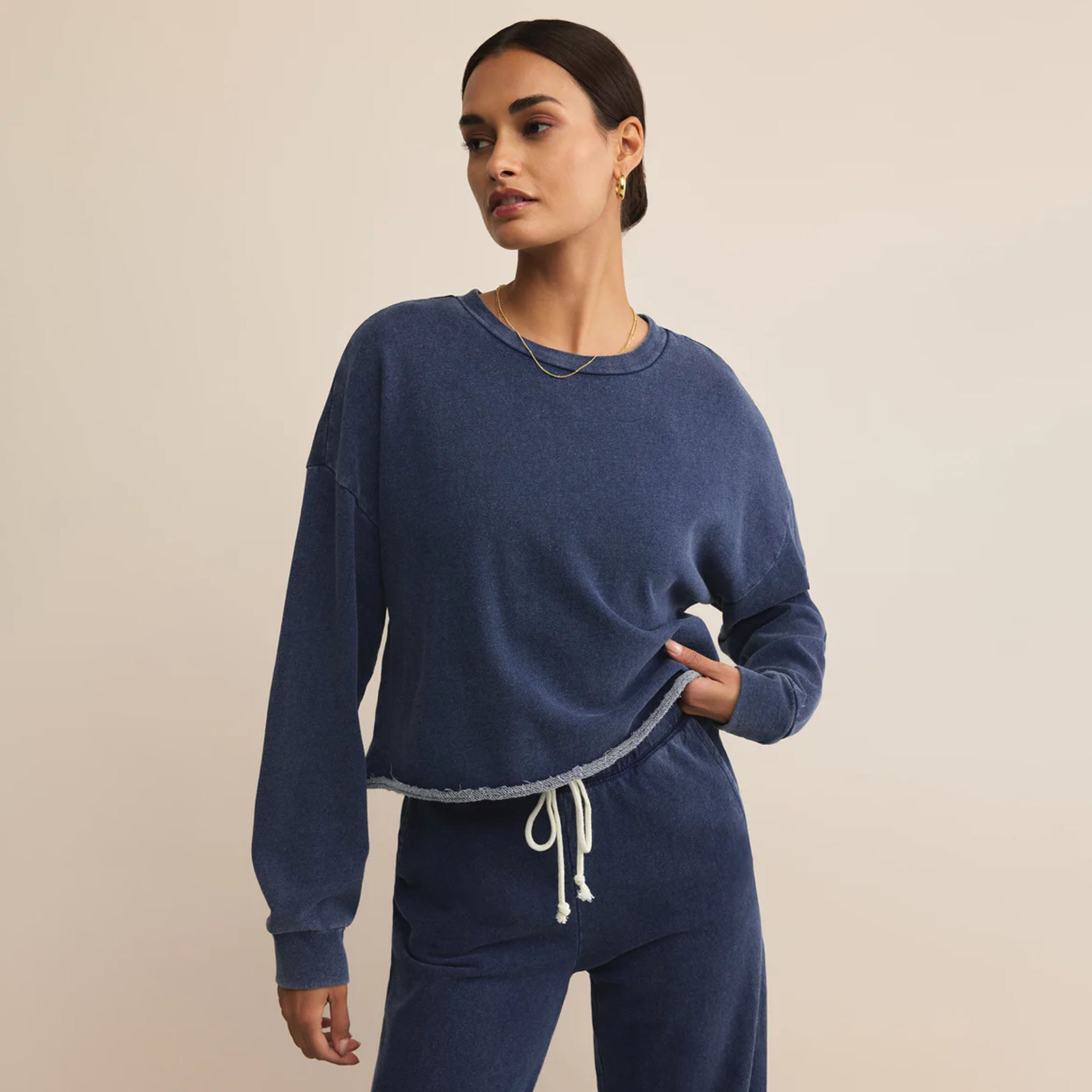 Woman wearing a blue sweatshirt and pants on a beige background