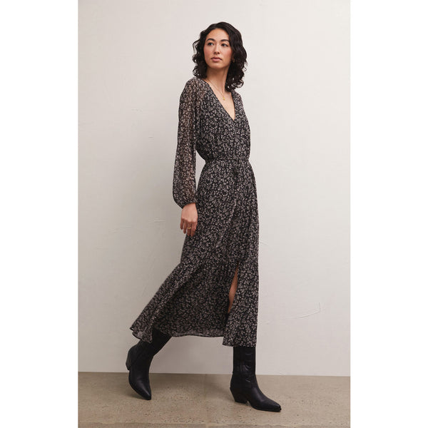 Brunette model wearing Z Supply Della Floral Midi Dress in Black with black boots in front of a white background