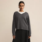 Woman wearing a gray sweater with a white collar against a beige background