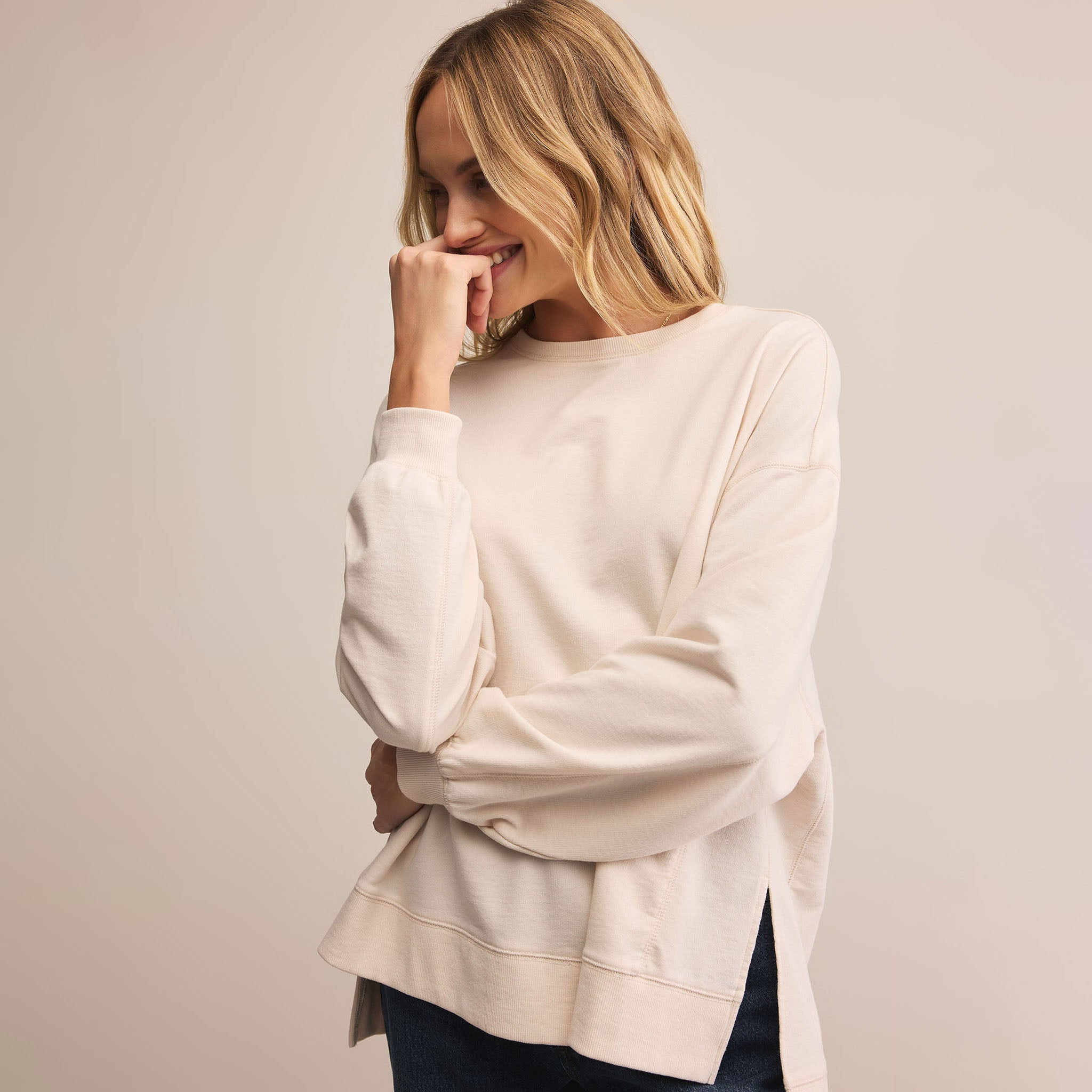 Woman wearing a cream-colored sweater against a plain background
