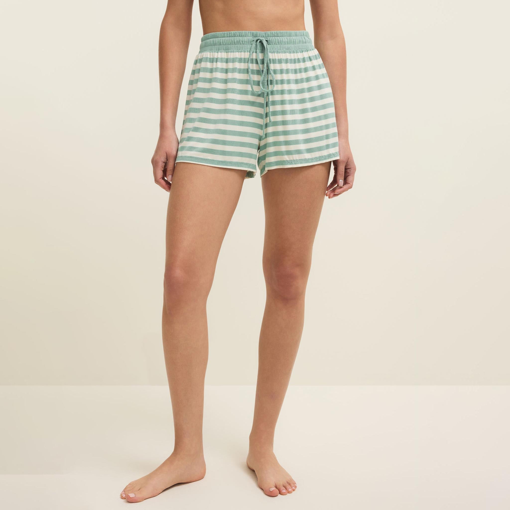 Person wearing green and white striped shorts on a beige background