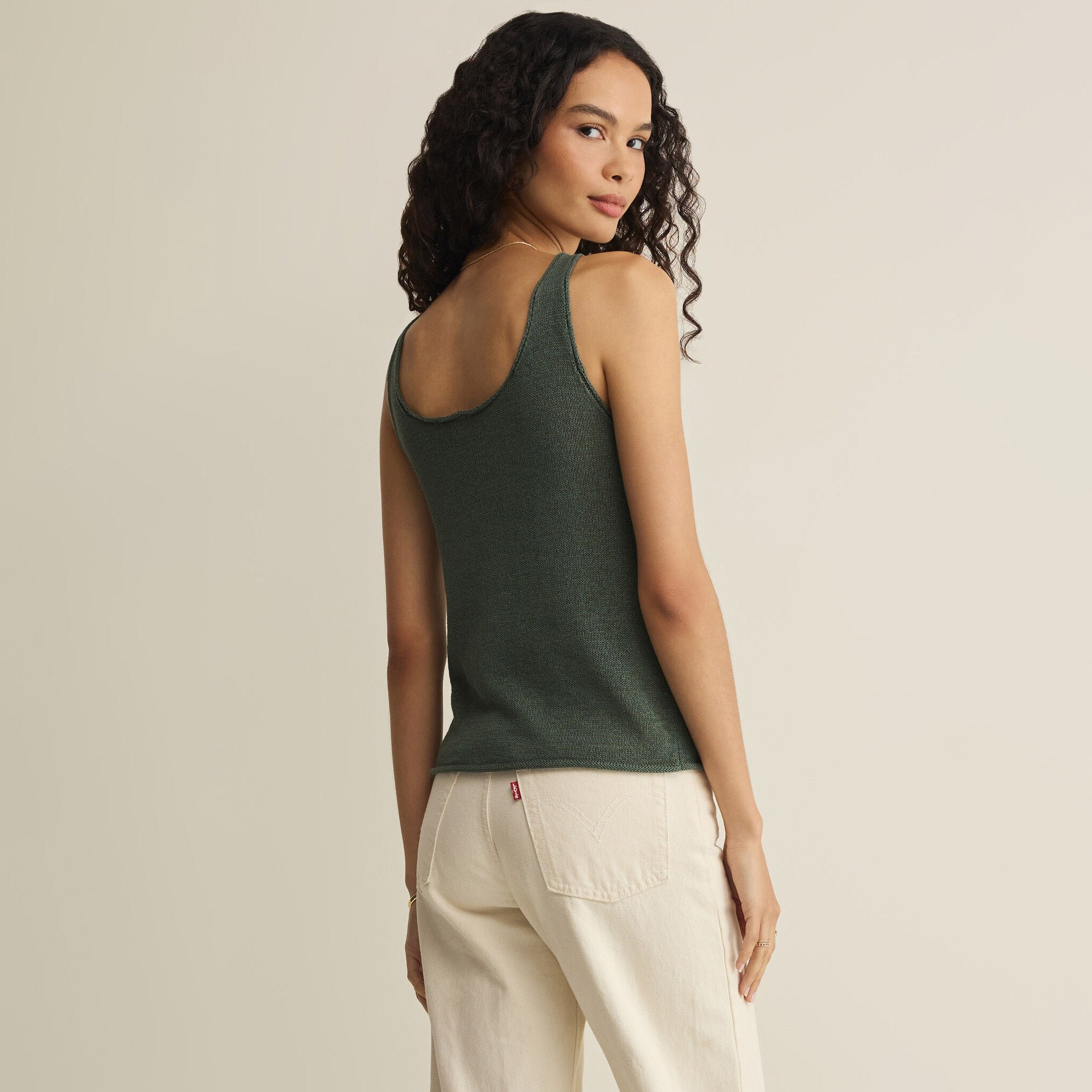 Woman wearing Z Supply Perch Sweater Tank in Everglade on plain background at Addison West.