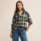 Woman wearing a plaid shirt and jeans against a beige background