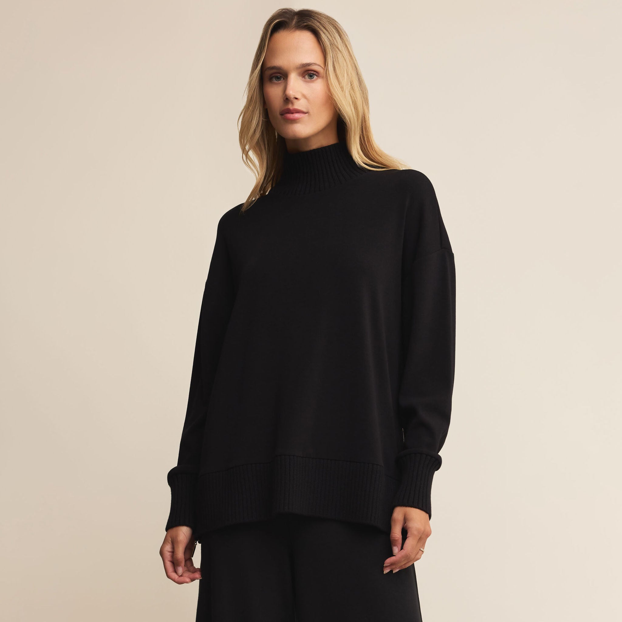 Woman wearing a black turtleneck sweater against a beige background