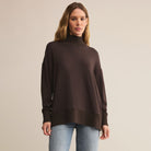 Woman wearing a brown turtleneck sweater against a beige background