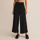 Person wearing black wide-leg pants on a beige background