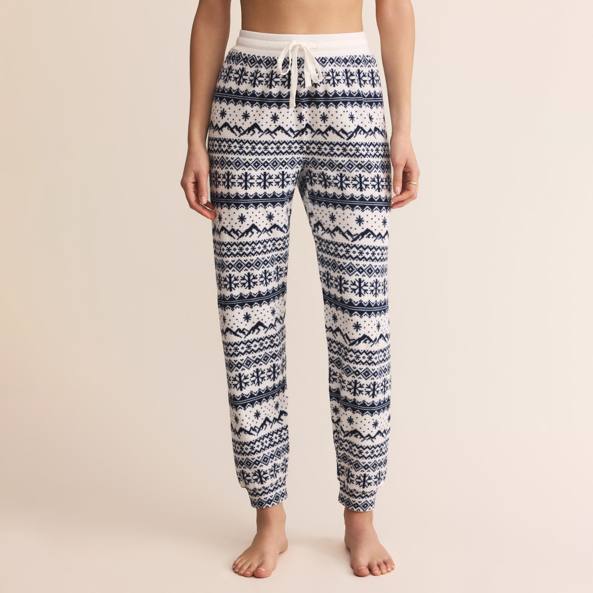 Person wearing navy and white patterned pajama pants on a beige background