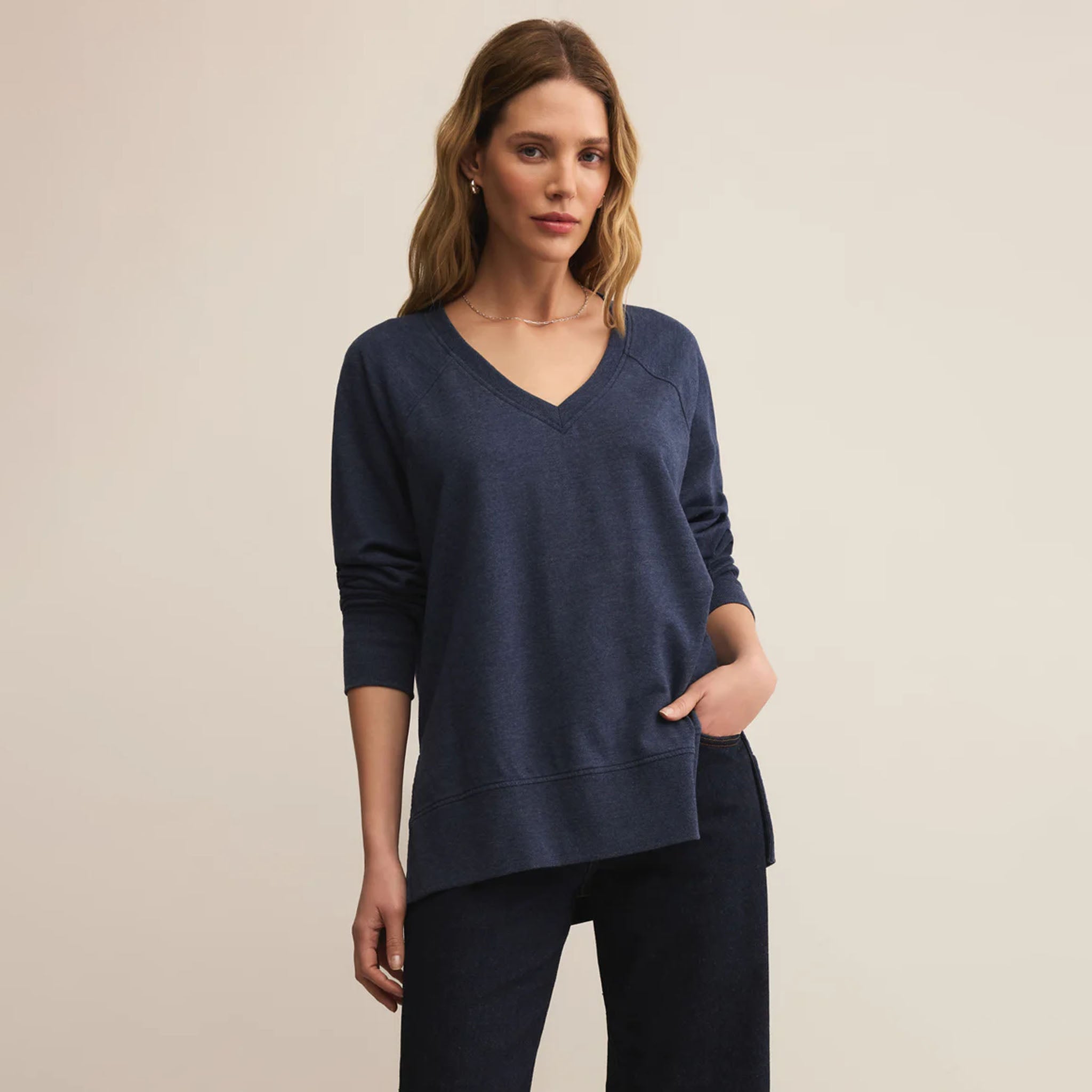 Woman wearing Z Supply Weekender V Neck in Blue Sapphire against a beige background