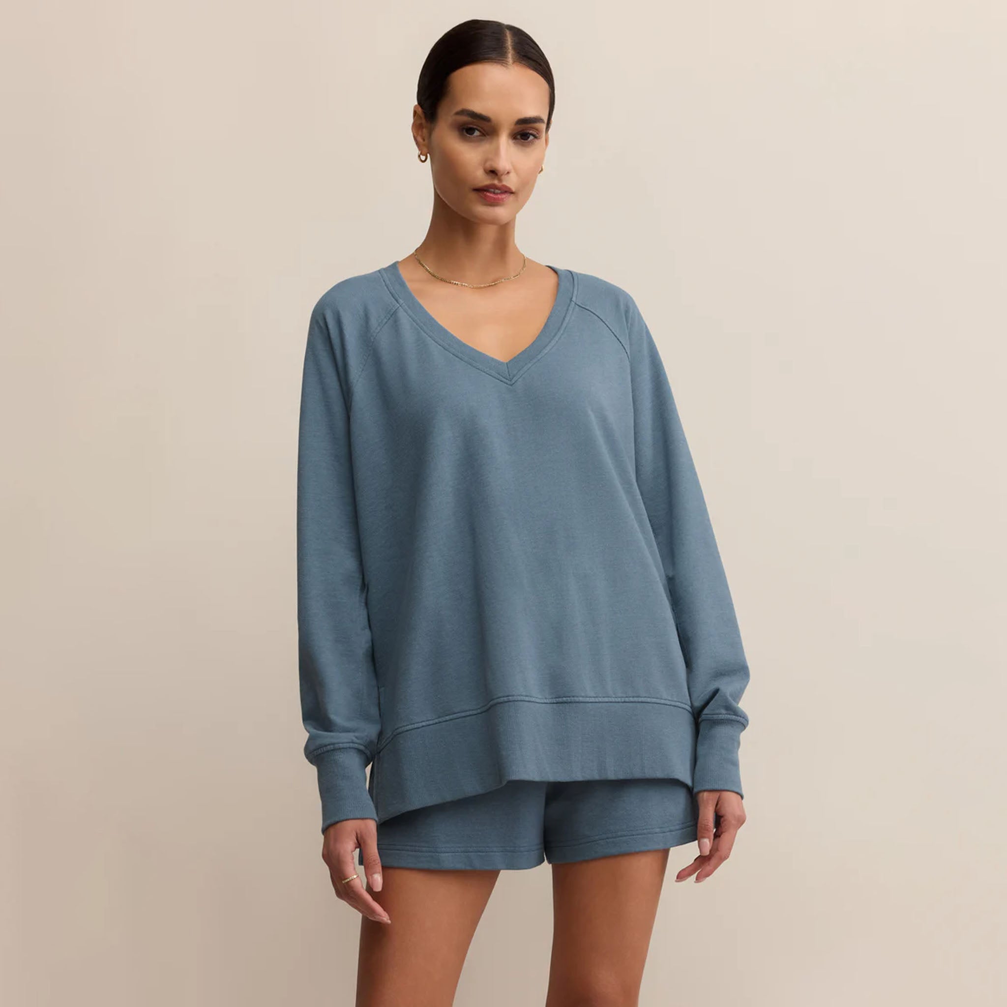 Woman wearing a blue sweatshirt and shorts set on a beige background