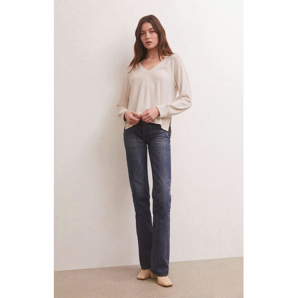 Model wearing jeans and Z Supply Wilder Cloud V-Neck Long Sleeve Top in Light Oatmeal in front of a white wall