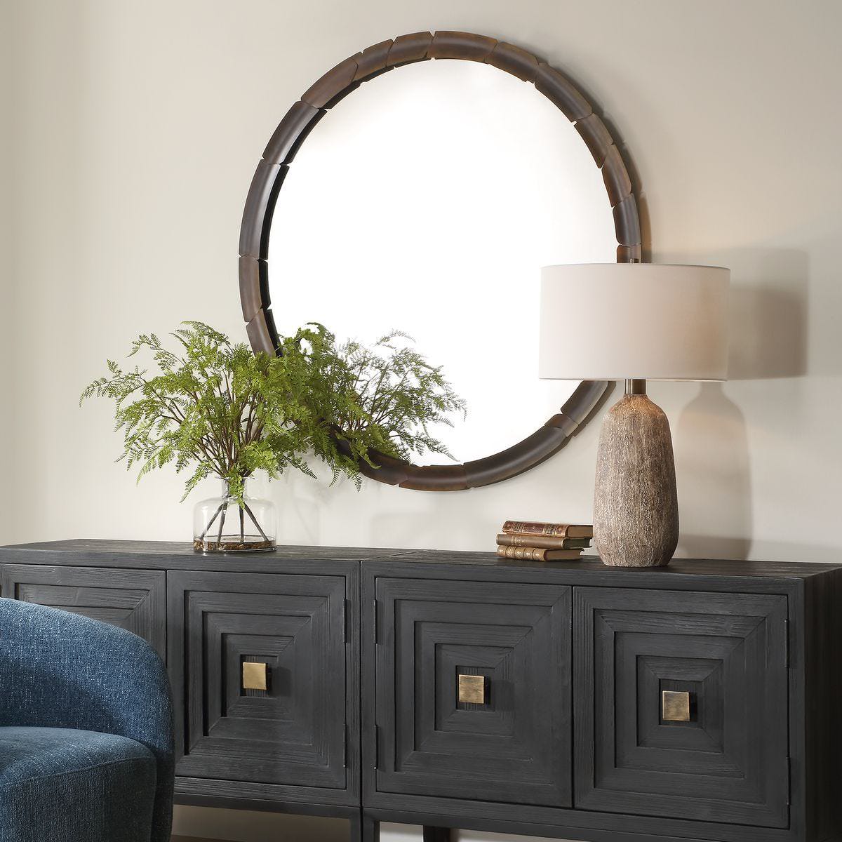 Augusta Round Accent Mirror on a beige wall above a table at Addison West