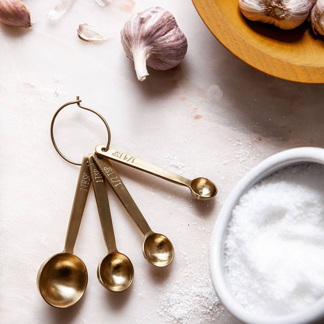 Stowe Measuring Spoons in Gold on a table at Addison West