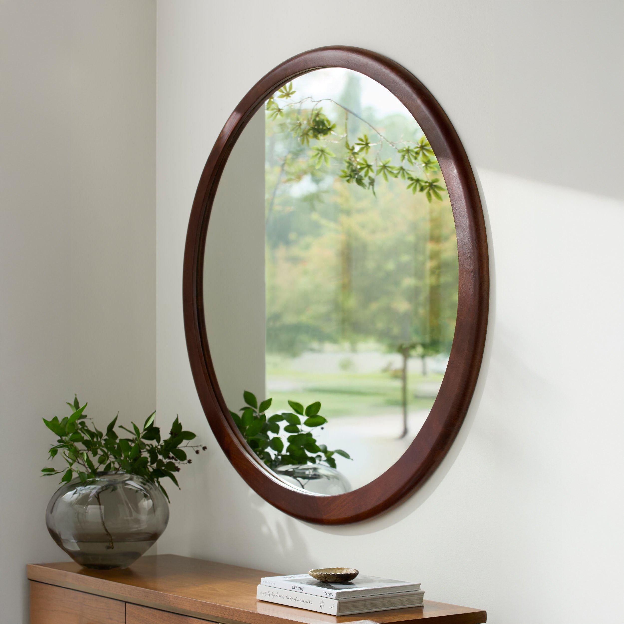 Brisbane Accent Mirror on a beige wall above a table at Addison West
