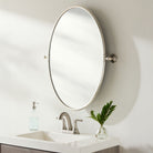 Oval Burnish Accent Mirror in Antiqued Silver on a white wall in a bathroom at Addison West